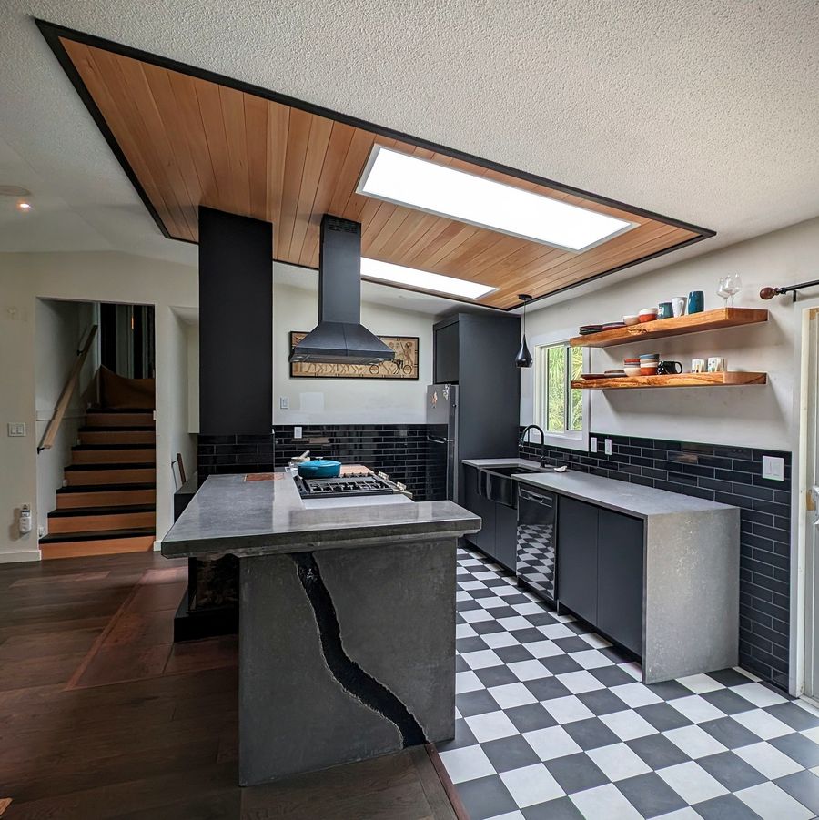 Finished kitchen in Ucluelet with a fir ceiling, skylights, a concrete island and a checkered tile floor.