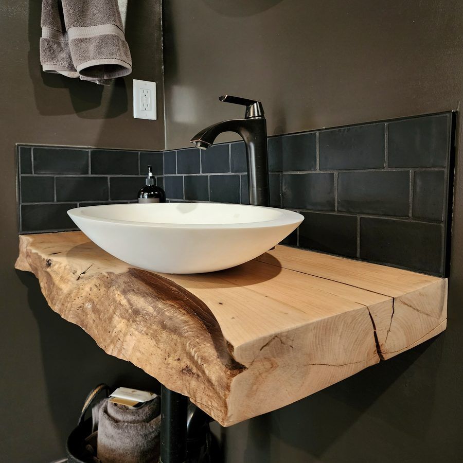 Bathroom vanity in Ucluelet: a live-edge slab with a white vessel sink and a black faucet.